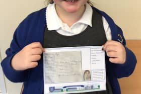 Poppy in Year 2, holding a post card of kindness, which was sent to a care home resident.