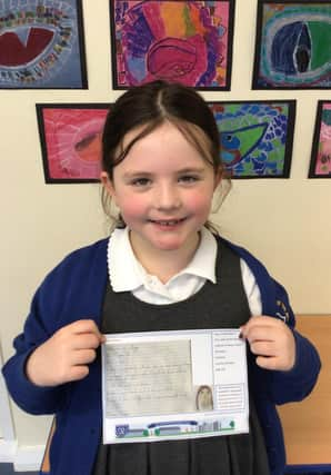 Poppy in Year 2, holding a post card of kindness, which was sent to a care home resident.