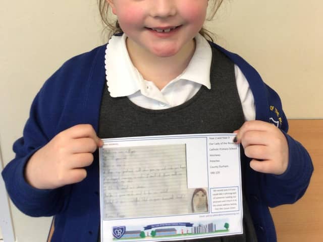 Poppy in Year 2, holding a post card of kindness, which was sent to a care home resident.