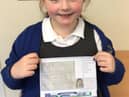 Poppy in Year 2, holding a post card of kindness, which was sent to a care home resident.
