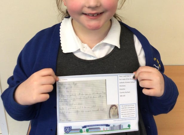 Poppy in Year 2, holding a post card of kindness, which was sent to a care home resident.