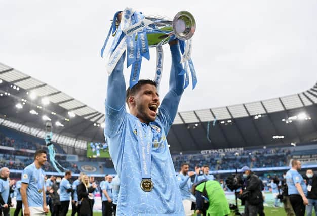 Ruben Dias of Manchester City celebrates with the Premier League Trophy as Manchester City are presented with the Trophy as they win the league following the Premier League match between Manchester City and Everton at Etihad Stadium on May 23, 2021 in Manchester, England.