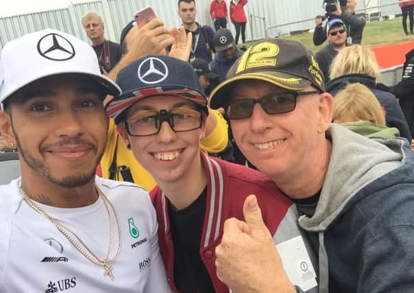 Formula One fan Luke Johnson with dad Jon and racing driver Lewis Hamilton.