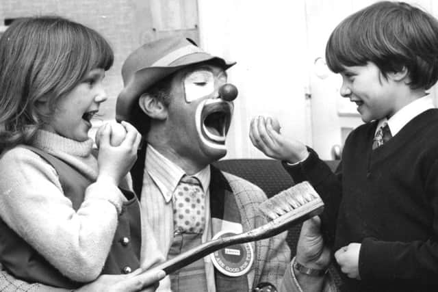 Pierre the clown shows Joanne Grainger aged 7 and Michael Reeder, 8, that eating apples is not only fun but also good for cleaning teeth in 1971.