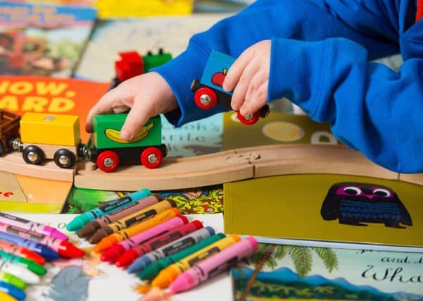 A toddler playing with a selection of children's toys, including wooden building blocks, crayons and a train set. Picture by PA Archive/PA Images