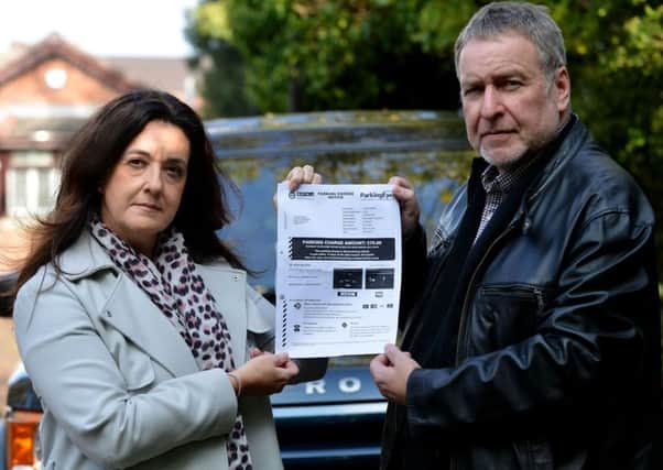 Lisa (49) and Ian (58) White with the parking ticket issued to them for overstay parking at a Asda store. Picture by FRANK REID
