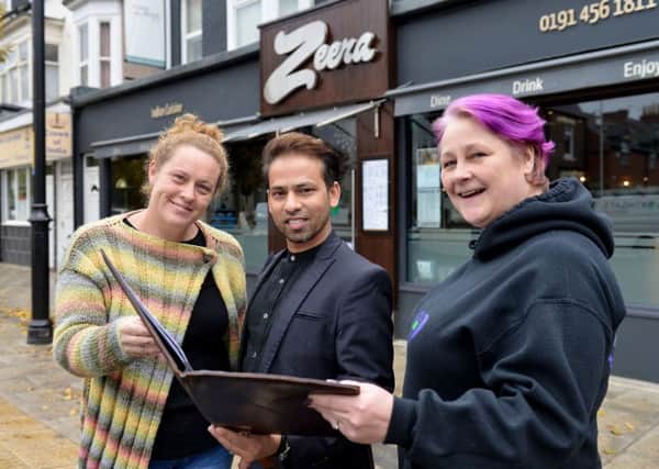Shahanoor Choudhury owner and director of Zeera Restaurant, holds a menu as Angie Commerford (left) and Jo Durkin from Hebburn Helps.