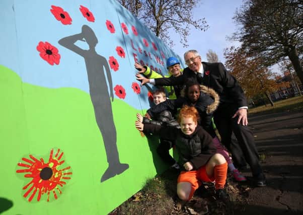 Children from Ashley Primary School unveil a First World War mural in the nearby West Park.