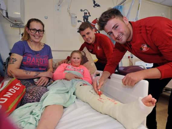 Ethan Robson signs a young fan's plaster cast, watched on by Max Power.