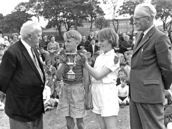 Mr T A Gedling, former headmaster of Cleadon Park Junior School, South Shields, presents the A J Wares Cup to the captains of Red House, the winning house at the school's sports day.  Looking on is headmaster, M P Ward.