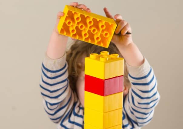 A young child at a nursery playing with large Lego blocks. Picture by PA