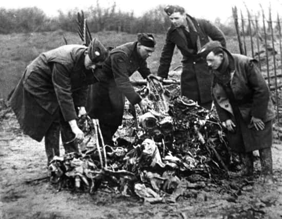 Servicemen hunt through the crumpled remains of the Heinkel which crashed and exploded in Beach Road in February 1941.