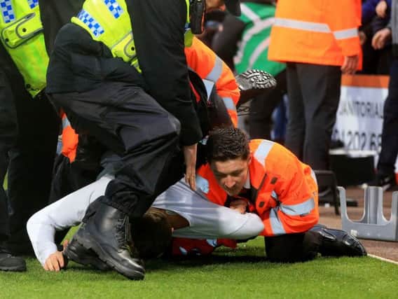 A Newcastle United fan is restrained by stewards and police after invading the pitch during the Premier League match at the Vitality Stadium, Bournemouth. Pic: Mark Kerton/PA Wire.
