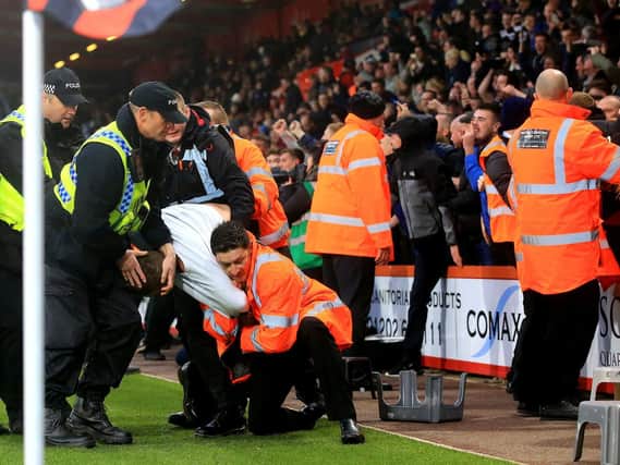 A Newcastle United fan is removed from the pitch by stewards and police at the end of the Premier League match at the Vitality Stadium, Bournemouth. Pic: Mark Kerton/PA Wire.