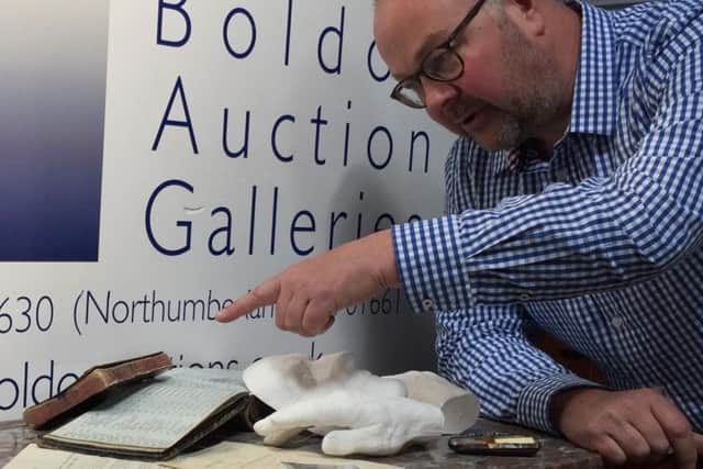Gallery director Giles Hodges with accessories including a plaster cast of Alberts, face and hands, Henrys notebook, and photographs and documents.