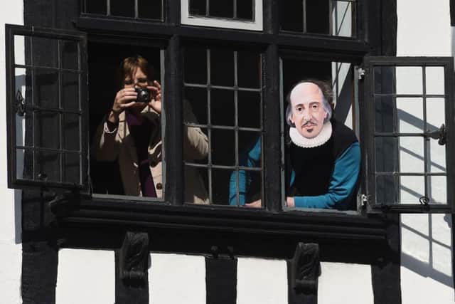 A man peers out of a window wearing a William Shakespeare mask during the parade marking 400 years since the death of the playwright in Stratford-upon-Avon, Warwickshire.
