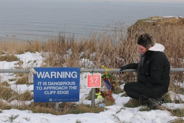 Jean Costello lays a wreath where her son drove over the cliffs.
