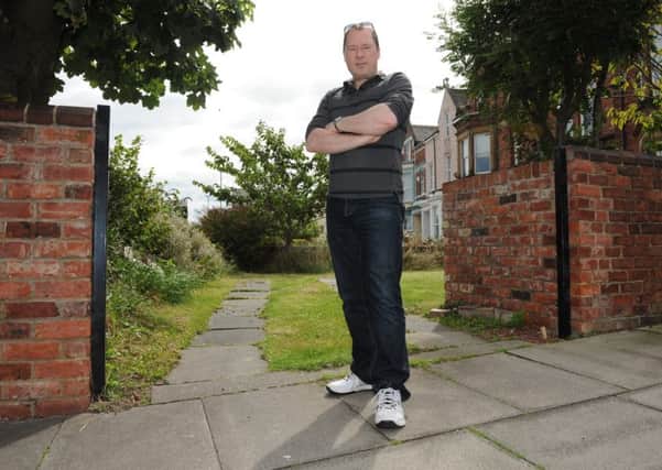 Gary Local stands where his stolen garden gates once stood.