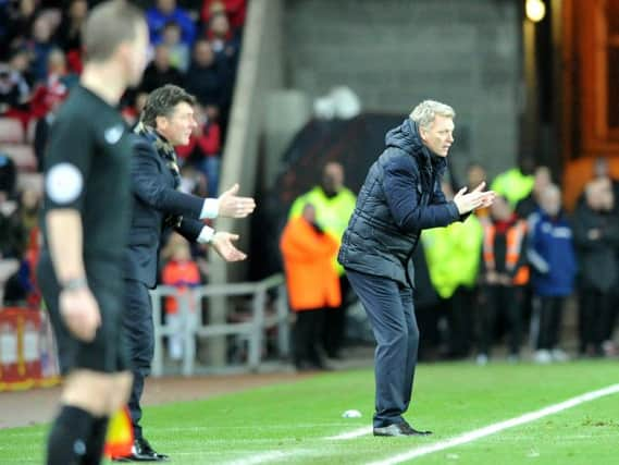 The two managers encourage their players from the technical area.