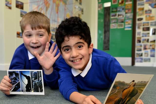 Fellgate Primary School pupils Will Ahmed (left) and Daniel Shavardi make their selection of postcards to be added to the vast collection on display in their classroom. Picture by FRANK REID