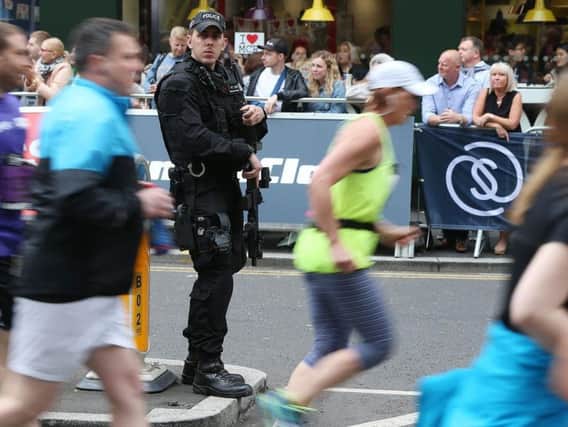 An armed police officer stands on the course during today's Great Run races in Manchester.