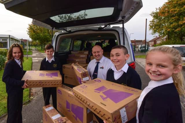 Younsters help unload the new computers bought by Grant Findlay