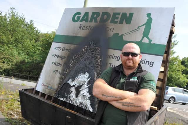 Garden Restoration's Darren Benstead with one of his two signs damaged in an arson attack.