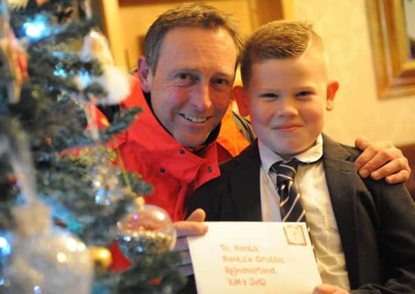 Ewan Thompson hands his letter to Santa to postman Trevor Brown so he can help deliver it.