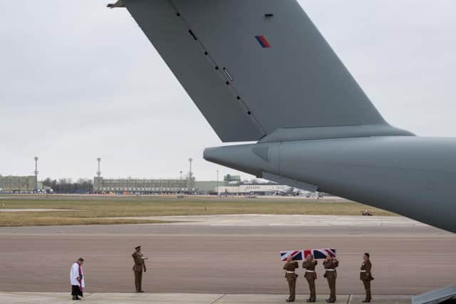 The coffin is saluted as it returns to the UK