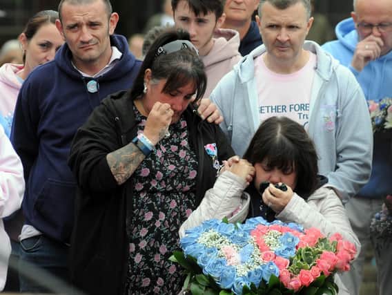 Parents Caroline Curry, wearing black jacket, Lisa Rutherford, with flowers, and Mark Rutherford, standing behind Lisa, at Tuesday's tribute to Chloe and Liam.