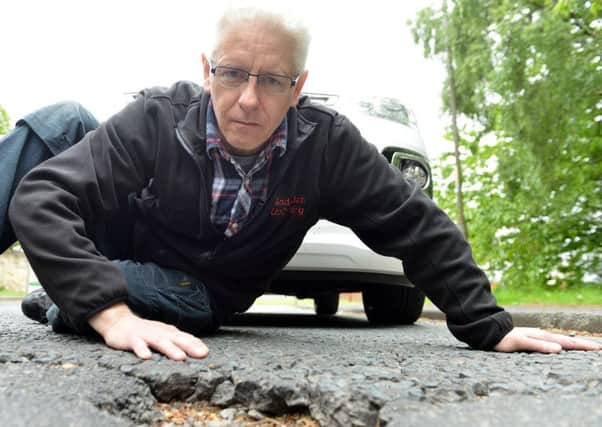 Andy Buddin (53) at one of the many potholes in Hill Park Road. Picture by FRANK REID
